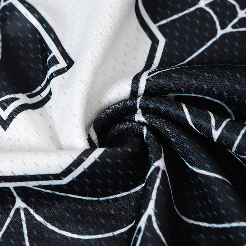 Black and white spider web mesh jersey fabric with bold gothic streetwear print in close-up