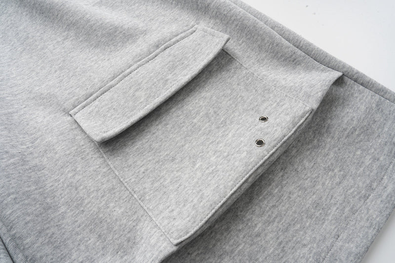 Close-up of gray cargo pocket flap with two metal eyelets on sweat shorts