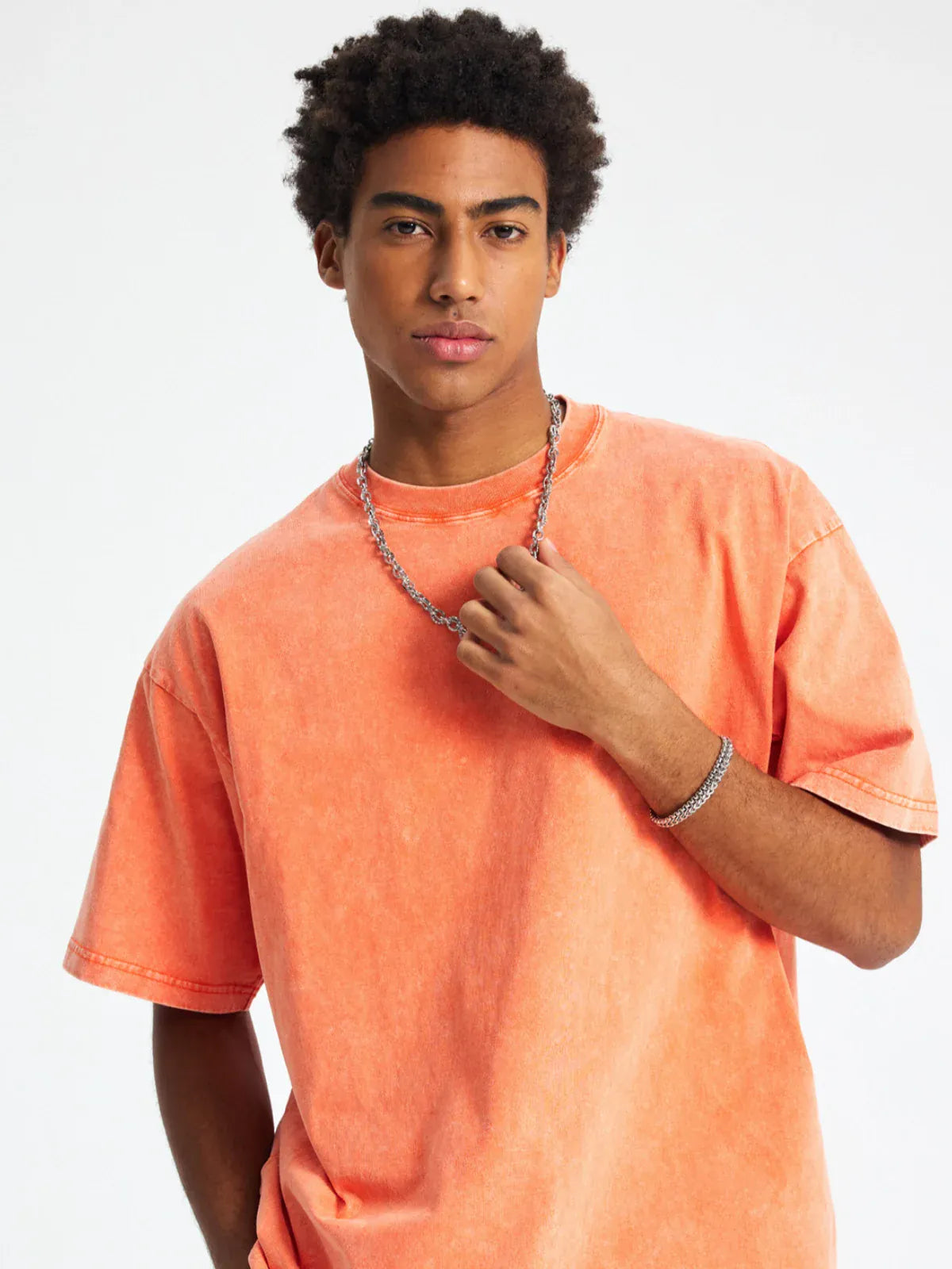 A person with short curly hair wears the Custom Anime Character Orange Washed T-Shirt - Personalized Anime Style Tee and a silver chain necklace, standing against a plain white background.