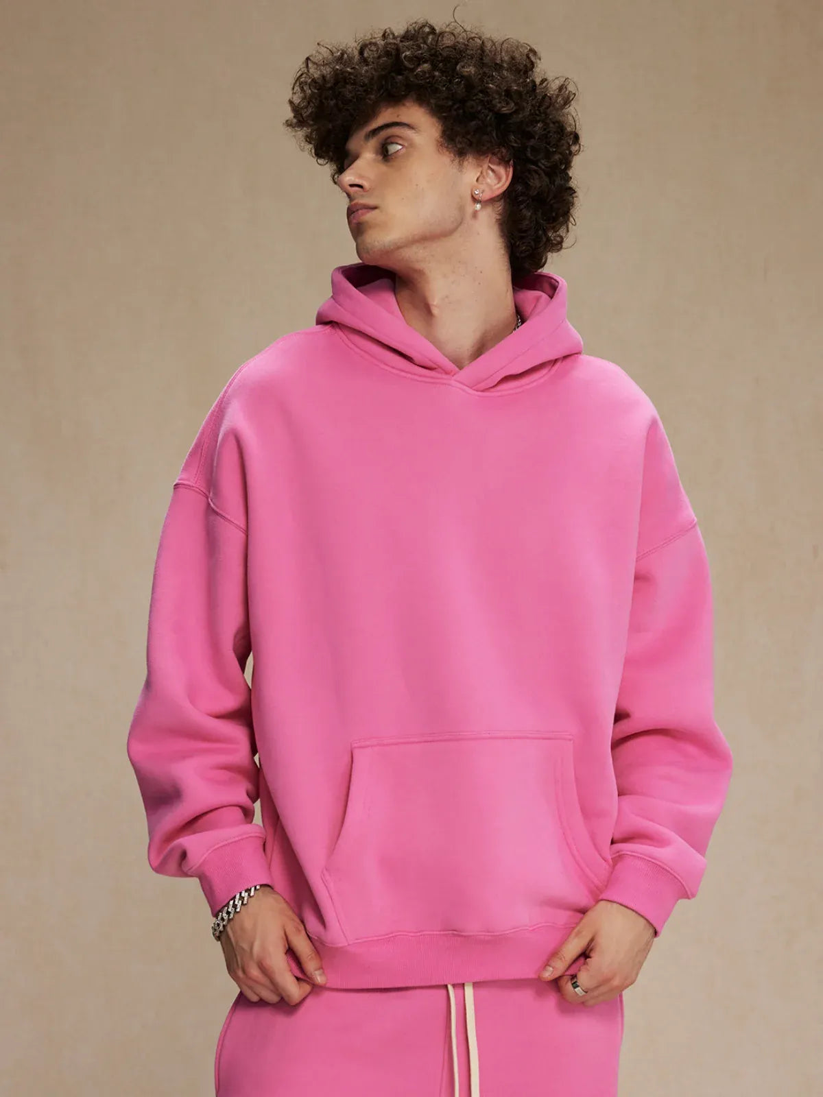 A person models the Custom Anime Character Bubblegum Pink Hoodie—Personalized 350GSM 100% Cotton Pullover—against a plain beige background, looking off to the side.