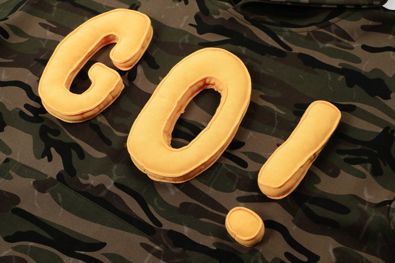 Close-up of yellow 3D puff GO! letters on camouflage hoodie