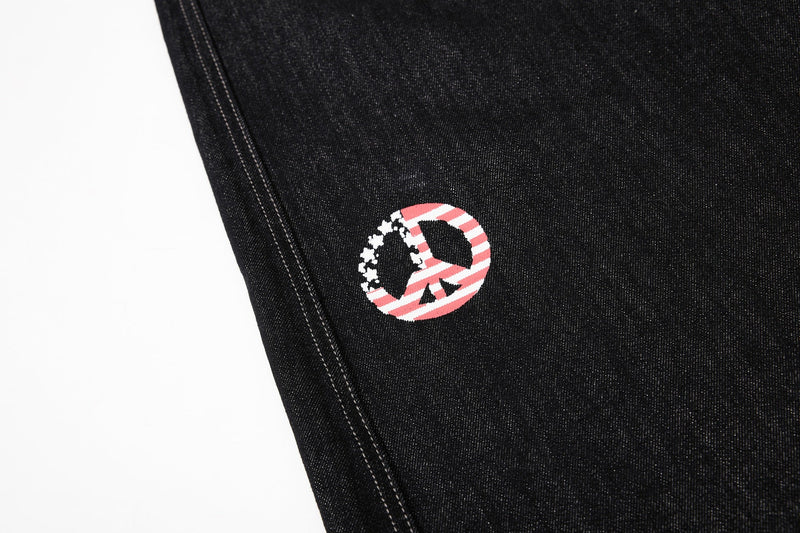 Small peace symbol graphic on black denim jeans