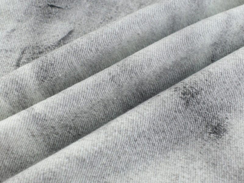 Close-up of light gray distressed denim fabric with soft folded texture