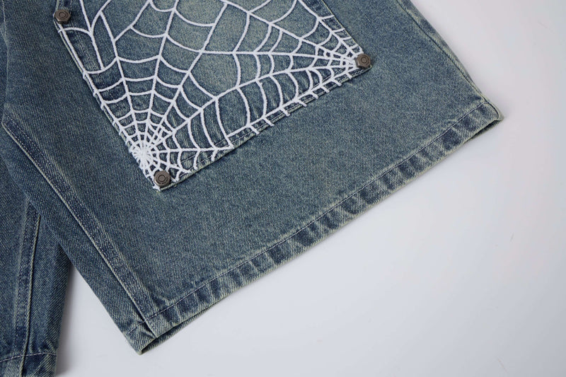 Close-up of light wash denim shorts spiderweb panel and hem with snap buttons