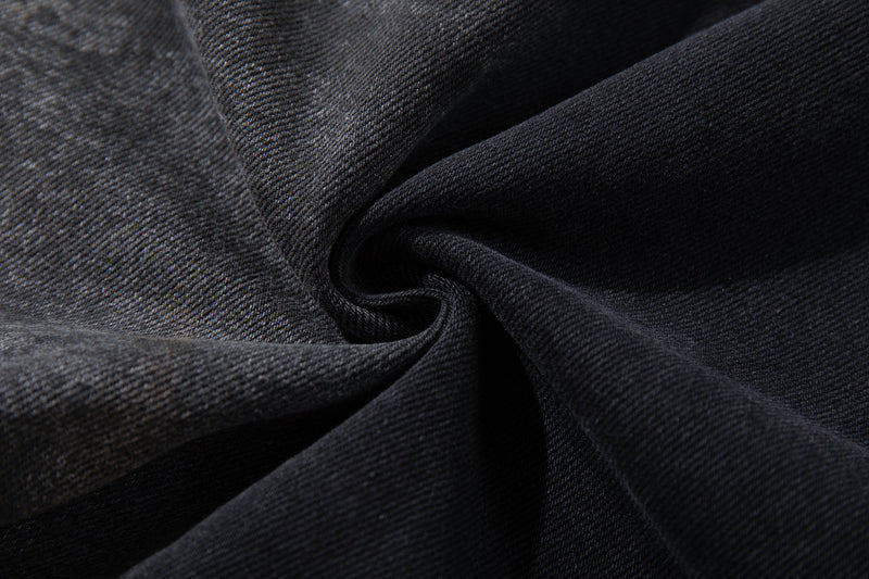 Close-up of dark denim fabric texture with smoky wash and visible diagonal twill weave