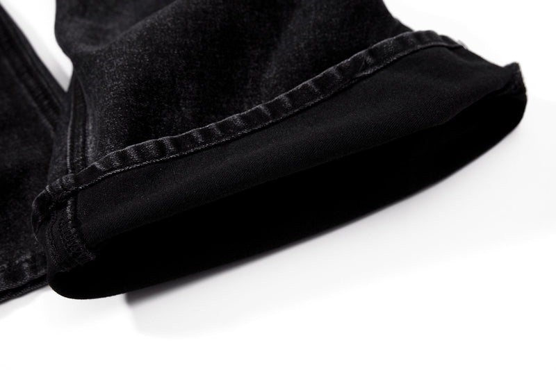 Close-up of black denim hem with folded flare cuff and seam stitching