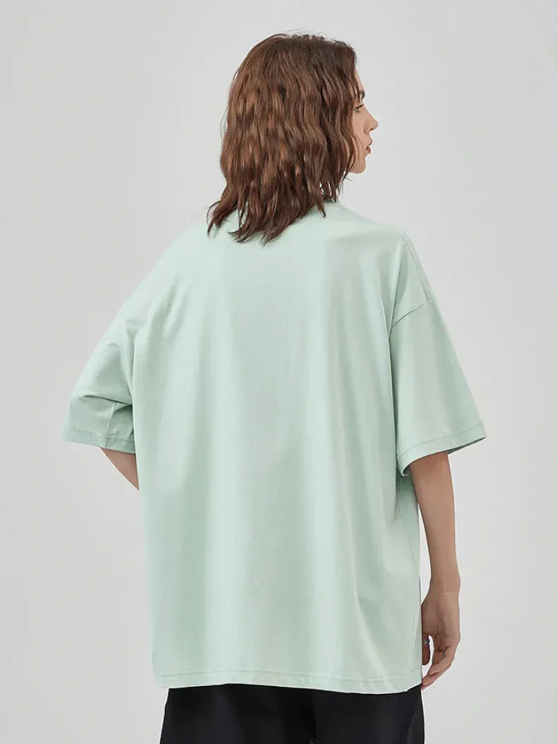 Someone with wavy brown hair is seen from behind, wearing a Custom Anime Character Mint Green T-Shirt (230GSM 100% cotton) along with black pants, standing against a plain background.