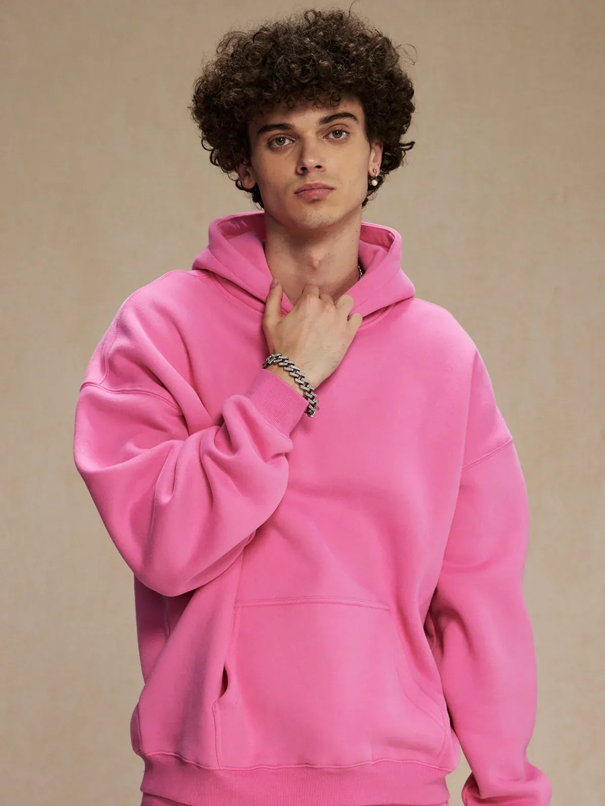 A young person with curly hair wears the Custom Anime Character Bubblegum Pink Hoodie—Personalized 350GSM 100% Cotton Pullover—and silver bracelets, posing against a plain beige background.