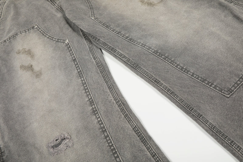 Close-up of gray jeans front legs showing distressed spots, patch pockets, and knee seam