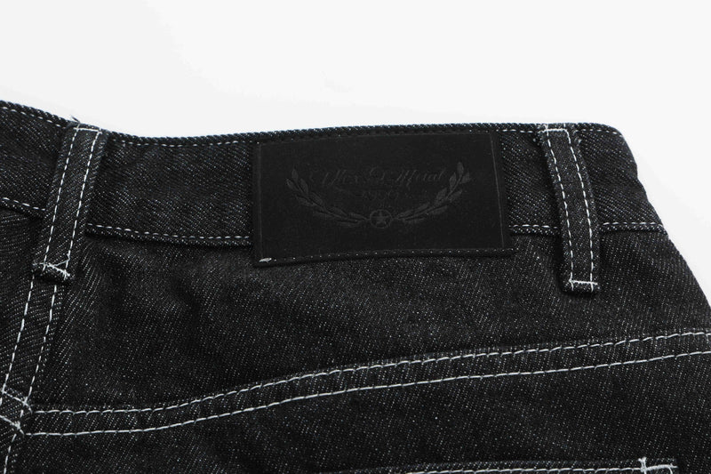 Black denim waistband close-up with embossed black patch label and white stitching