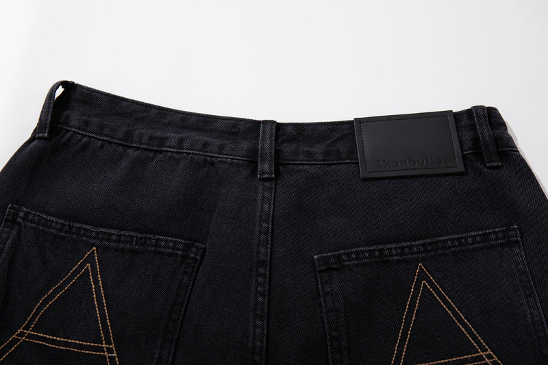 Close-up of waistband on black carpenter jeans with black leather-style logo patch