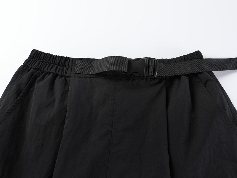Close-up of black shorts waistband with buckle belt and elastic gathering