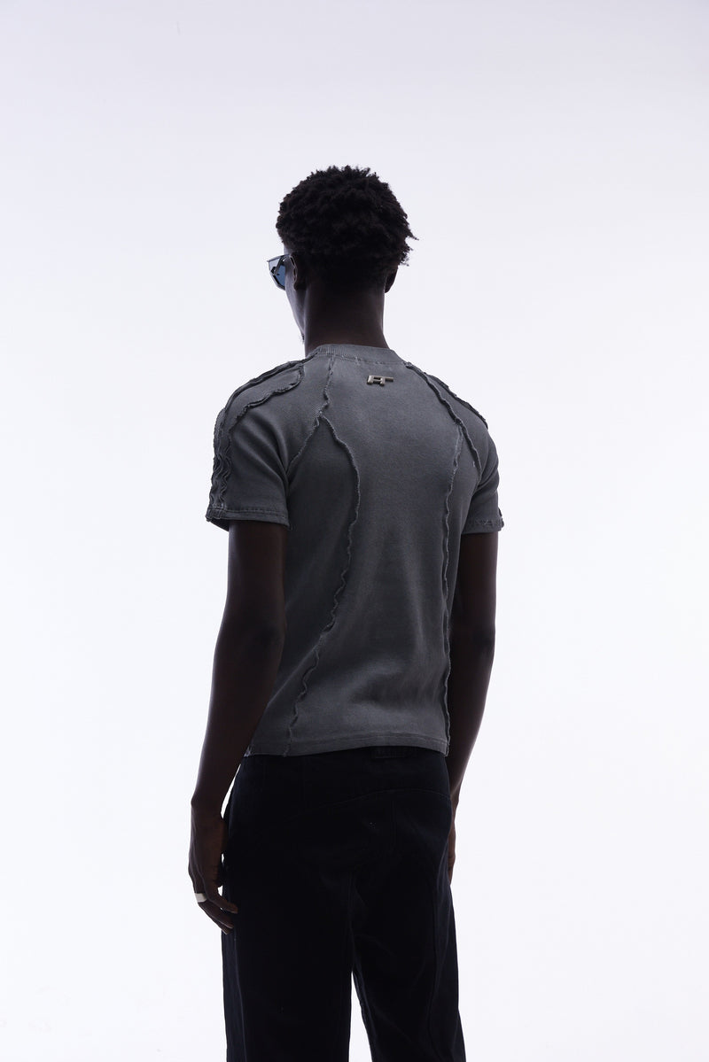 Back view of a model wearing a gray raw seam compression tee with deconstructed stitching and streetwear styling