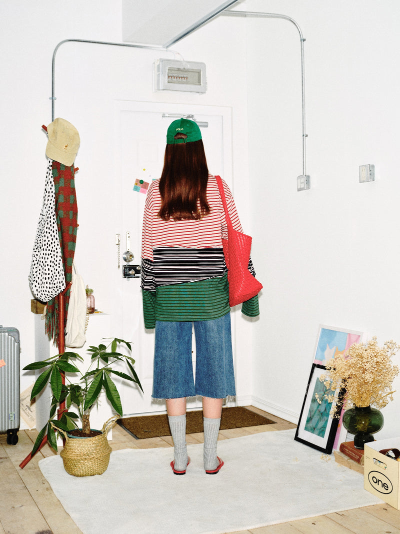 Back view of model wearing color-block striped long sleeve tee and red bag