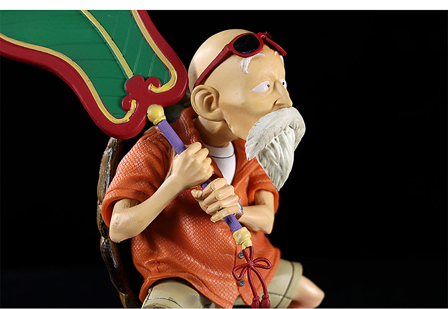 The Seakoff Master Roshi Collectible Figure features an elderly man with a white beard and sunglasses, seated on a brown turtle shell, wearing an orange shirt, and holding a large green Banana Fan. An ideal addition to any Dragon Ball collection, the stark black background enhances this unique 18cm figure&