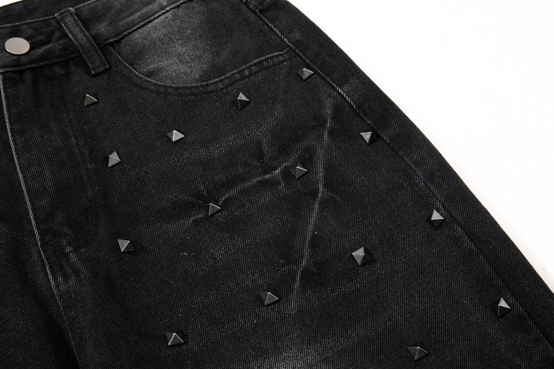 Front upper thigh of black studded jeans with curved pocket and waistband