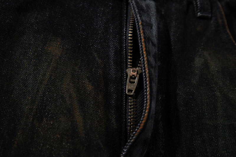 Close-up of the front fly with metal zipper on dark washed denim