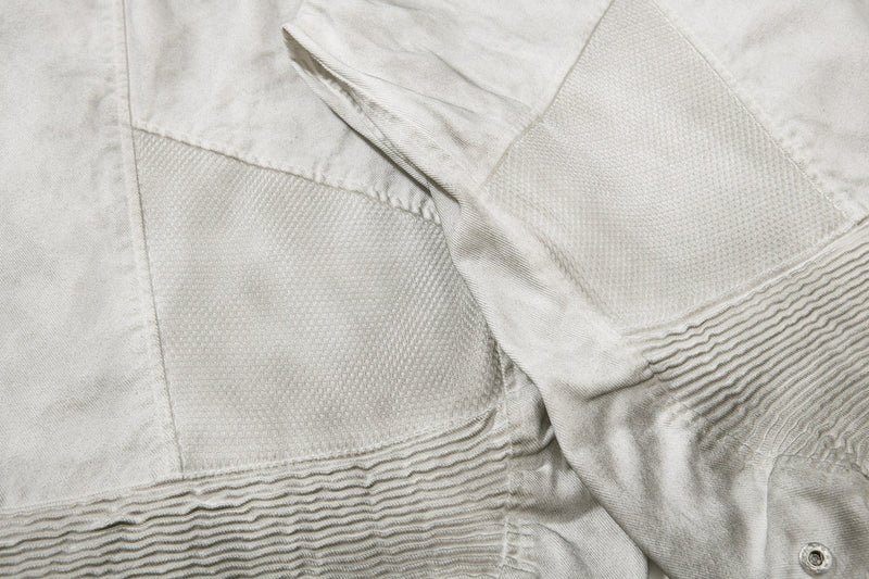 Close-up of textured mesh-like side panels and lower hem on light gray shorts