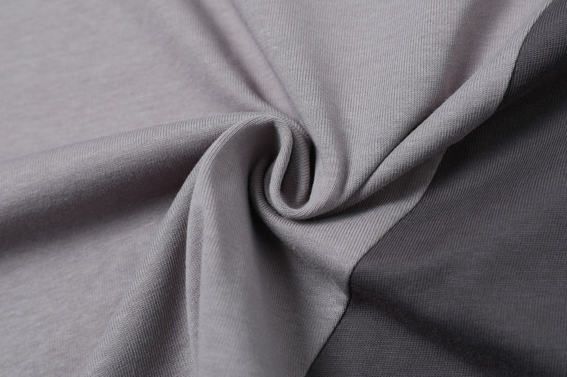 Close-up of gray split-panel cotton T-shirt fabric with a textured knit and draped fold detail