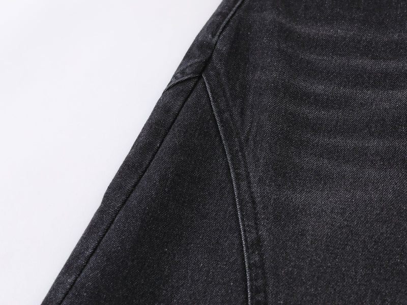 Close-up of black denim leg seam and panel stitching