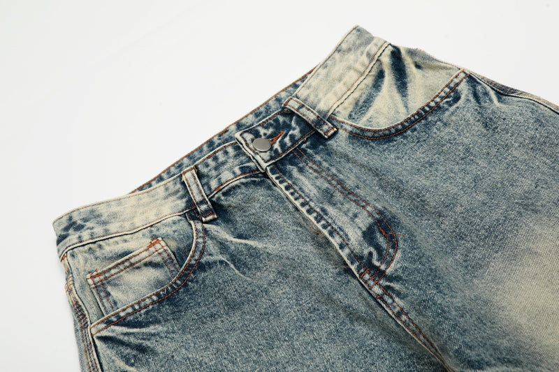 Close-up of light wash jeans waistband with belt loops, button closure, and front pocket seam