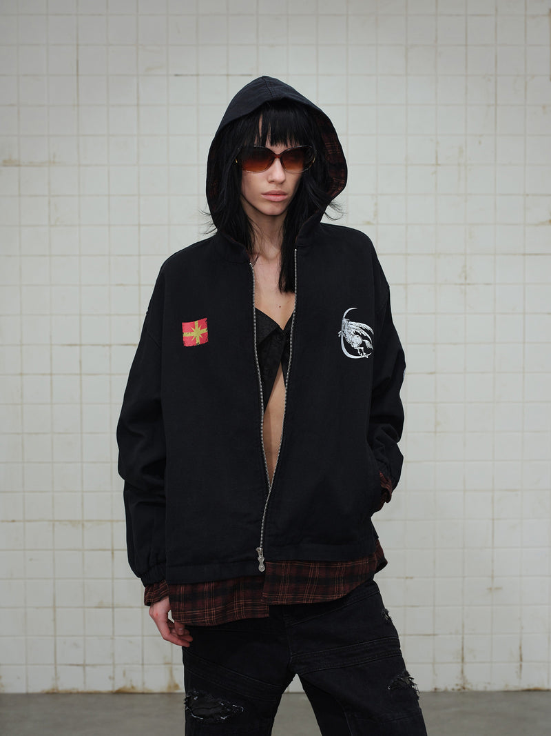 Model wearing black zip hoodie with hood up, front graphics, and red plaid lining visible
