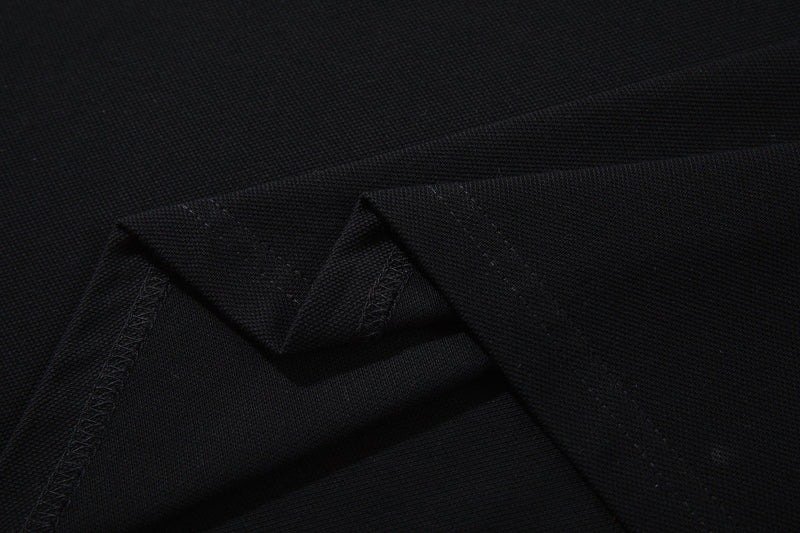 Close-up of black gothic polo tee fabric with angular seam details and oversized streetwear texture