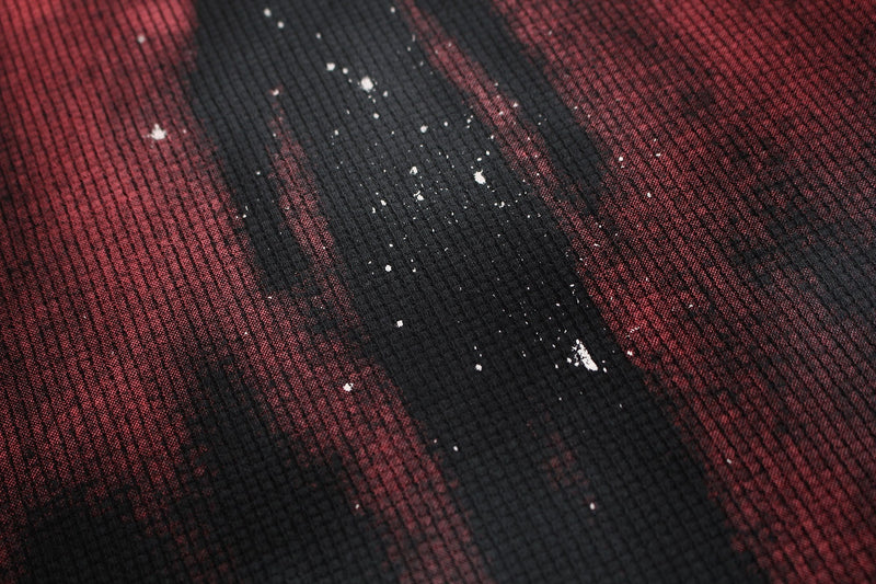 Close-up of a washed black and burgundy oversized tee with distressed shadow figure print and textured fabric detail