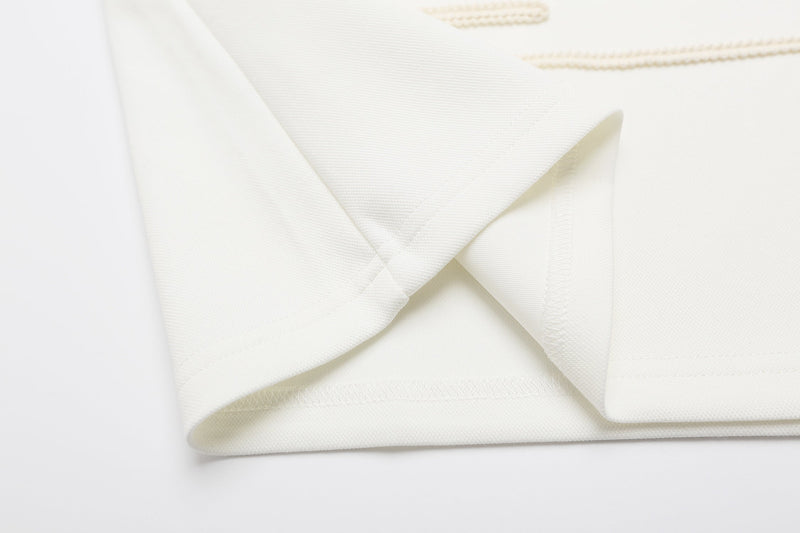 Close-up of a white military braid polo shirt with epaulette detail and textured rope embroidery trim