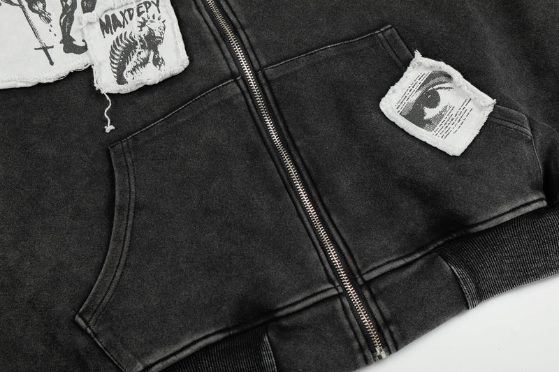 Close-up of black hoodie front pockets, zipper, and graphic patches on the chest