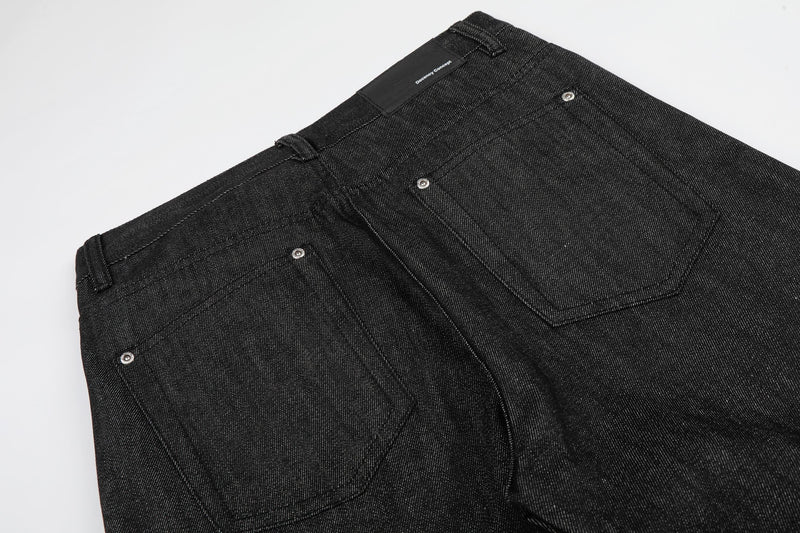 Back view close-up of black jeans waistband and rear pockets with brand label