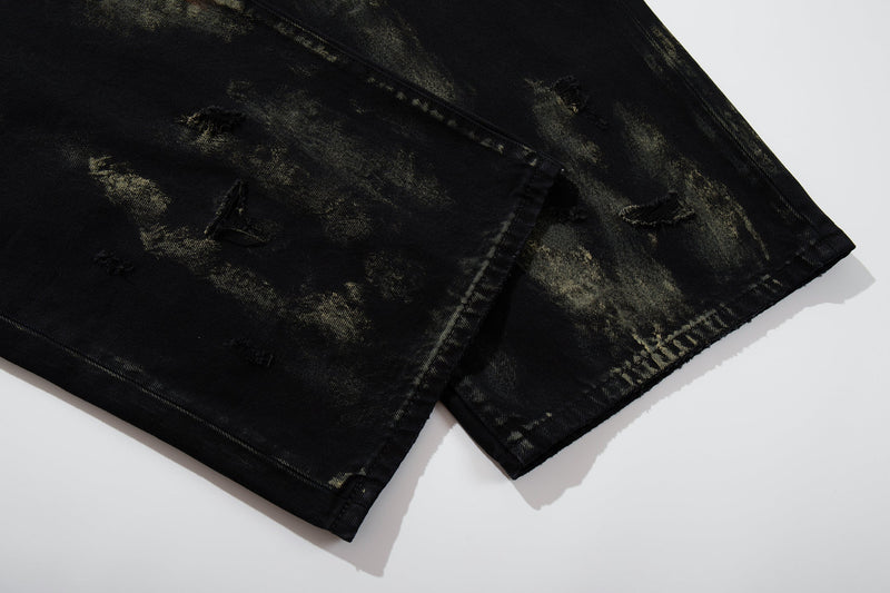 Close-up of hem on black denim jeans with distressed wash and frayed edges