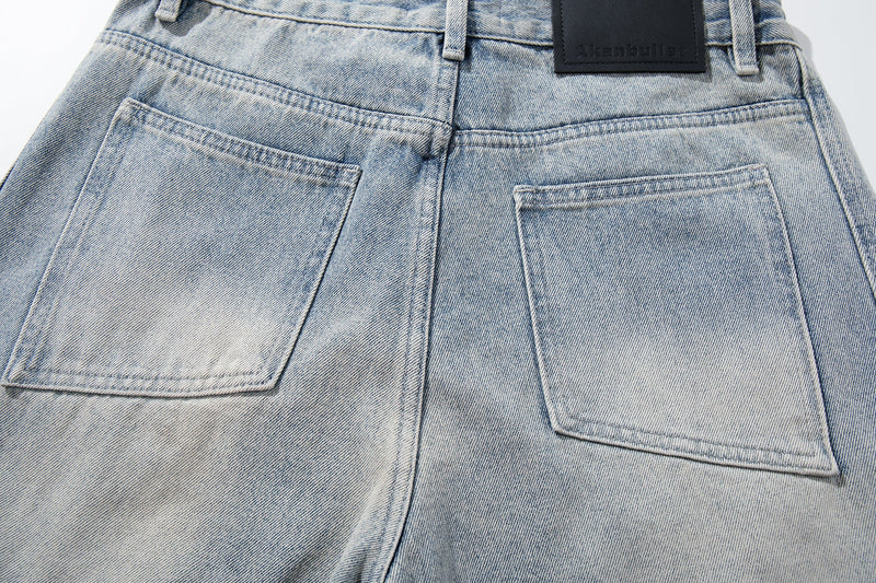 Close-up of back pockets on light wash denim jeans with faded wash and topstitching