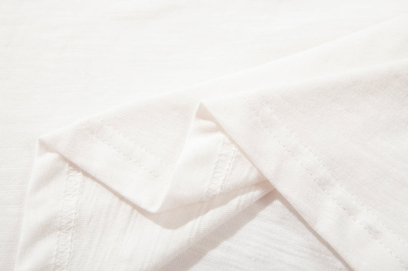 Close-up of a white cotton T-shirt hem and sleeve with subtle seams and soft fabric texture