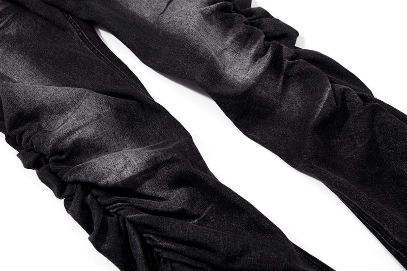 Stacked black flare jean legs with ruched folds and washed finish