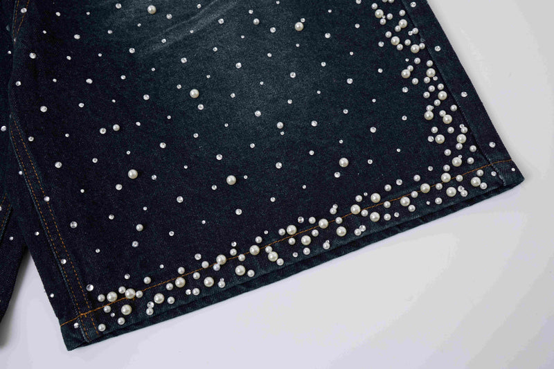 Bottom hem of black denim shorts with pearl studs