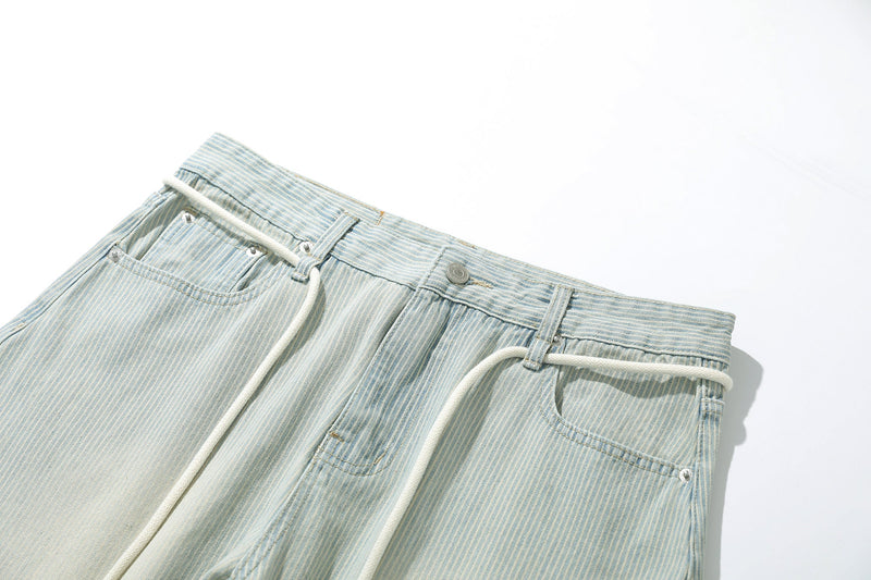 Close-up of the waistband and front pockets on light wash striped denim pants