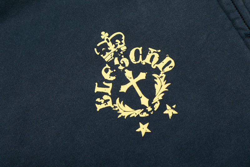 Close-up of small gold crest graphic with cross and floral details on navy fabric