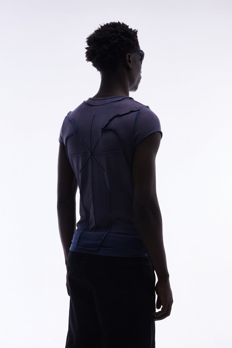 Back view of a model wearing a navy sculpted cotton tee with raw seam panel detailing and an avant-garde fit