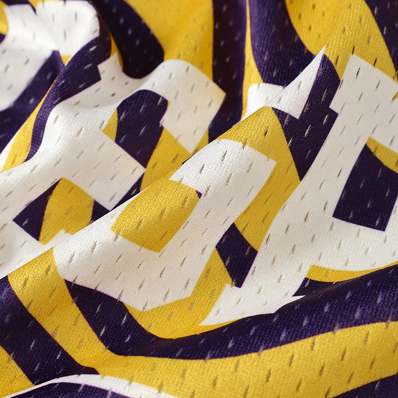 Close-up of psychedelic swirl jersey fabric with bold purple, yellow, and white geometric pattern and mesh texture