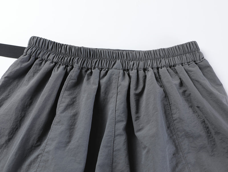 Close-up of gray shorts back waistband with elastic gathering and belt end