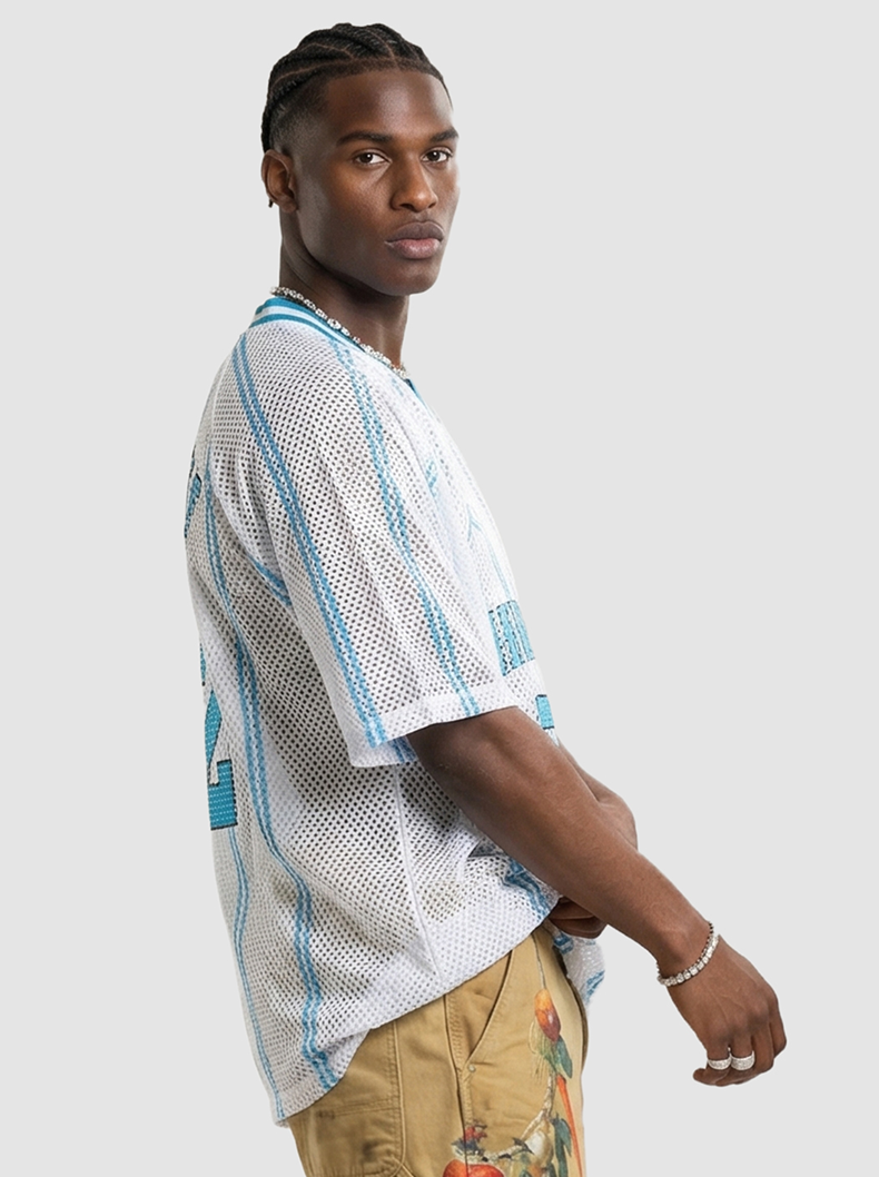 Model wearing a white mesh jersey T-shirt with blue accents and number 2, styled with tan streetwear pants