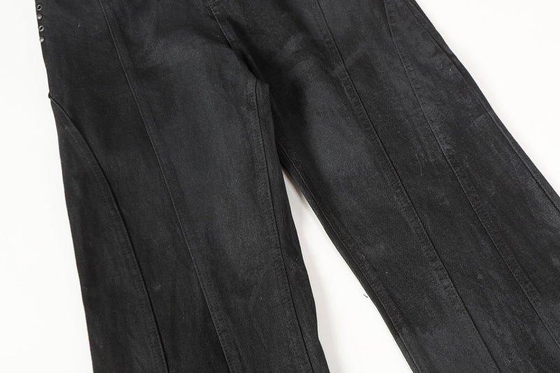 Close-up of black denim legs showing vertical panel seams and wide cut