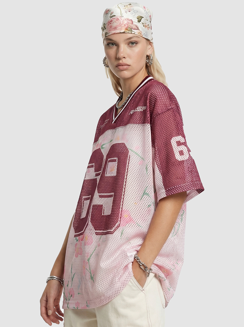 Model wearing a burgundy floral mesh jersey T-shirt with number 69, floral headscarf, and cream pants