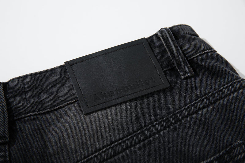 Close-up of black leather logo patch on the back waistband of faded denim jeans