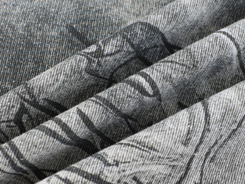 Close-up of crinkled gray denim fabric with black graffiti print