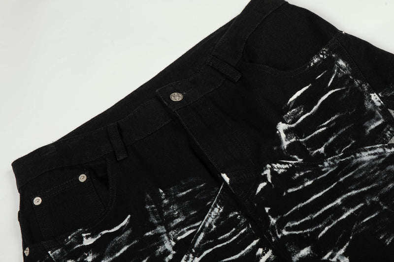 Close-up of black denim waistband with button, belt loops, and brush-stroke print