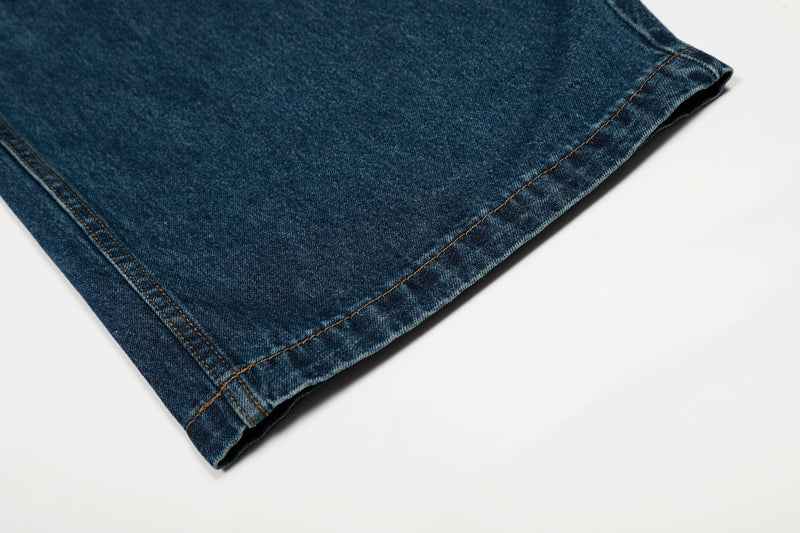 Close-up of the hem on deep indigo denim with orange topstitching