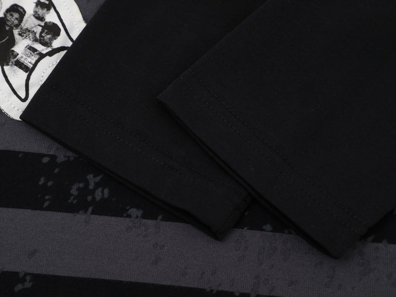Close-up of black long sleeve cuff and striped body with printed patch detail