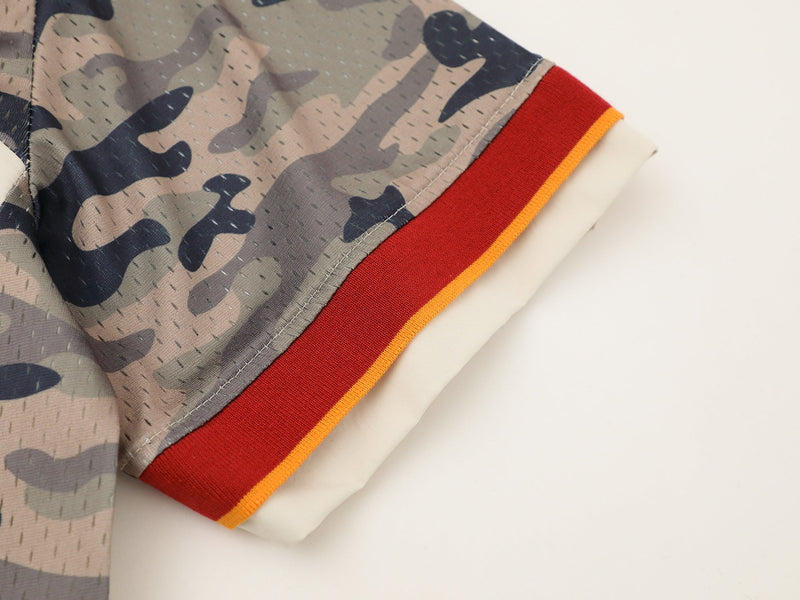 Close-up of a camo panel shirt sleeve with red and orange ribbed trim and cream fabric detail